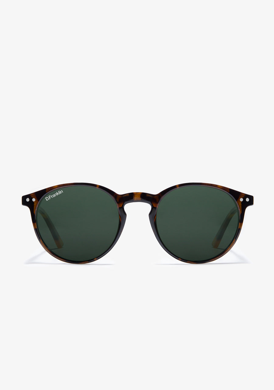 A pair of round-framed sunglasses with black polarized lenses and a tortoiseshell pattern on the frame. The brand logo is visible on the side.